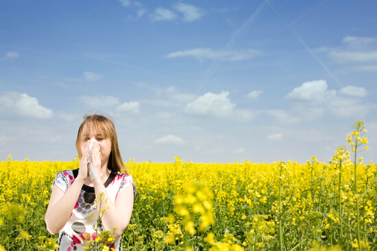 Girl suffering with allergies in a field of flowers
